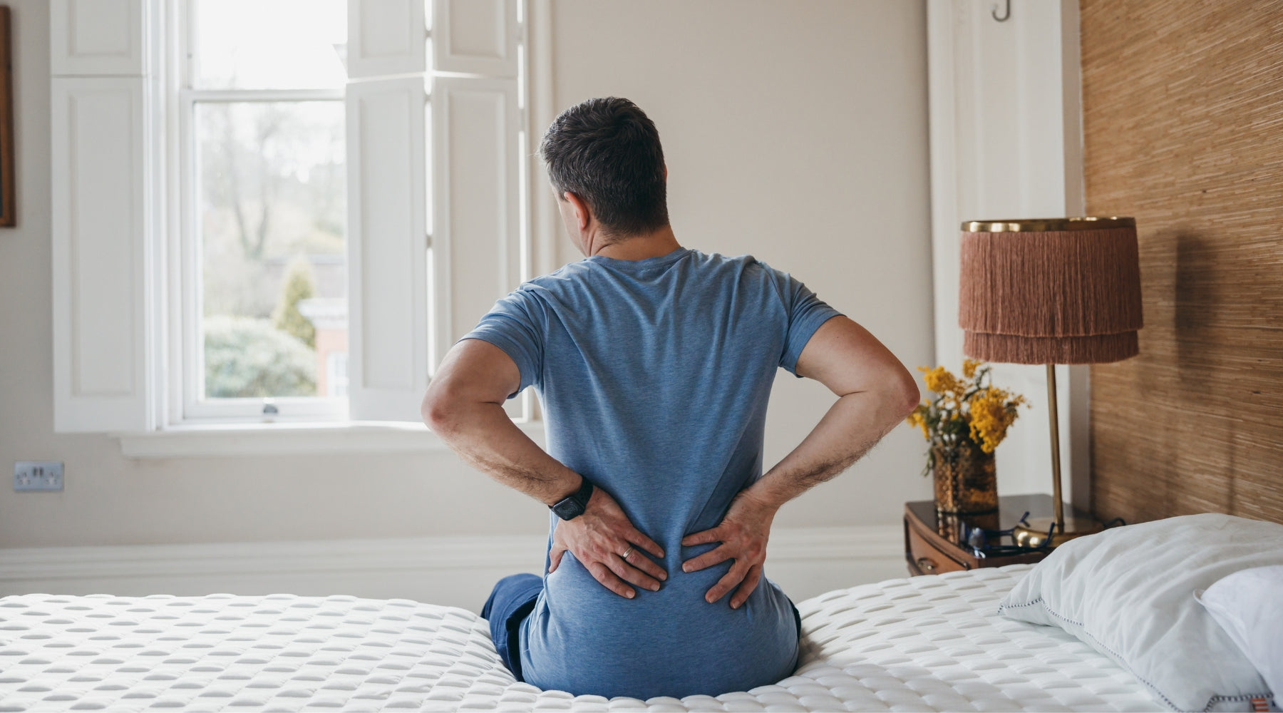 man touching his lower back