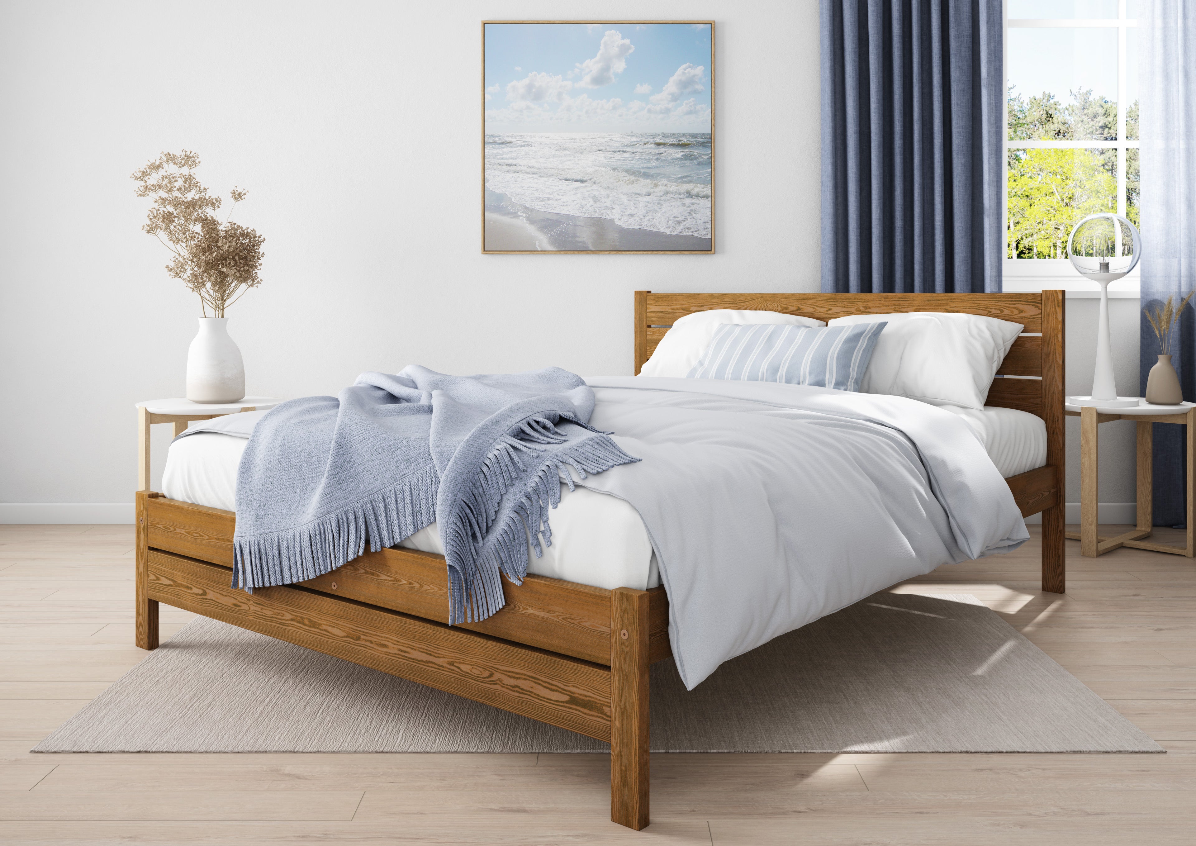 Wooden bed with white bedding and blue blanket in a bright bedroom