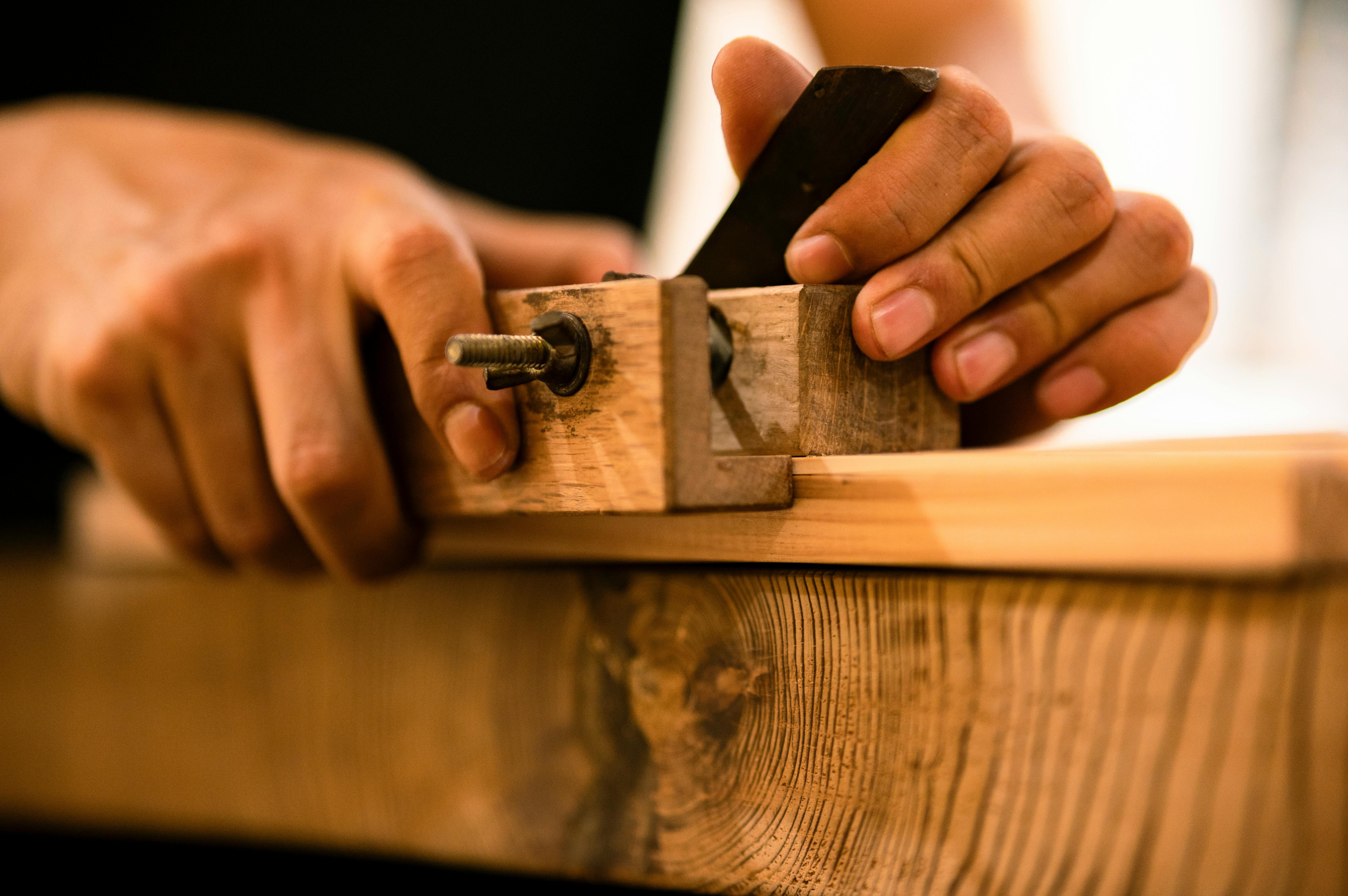 Person using a hand plane on wooden surface