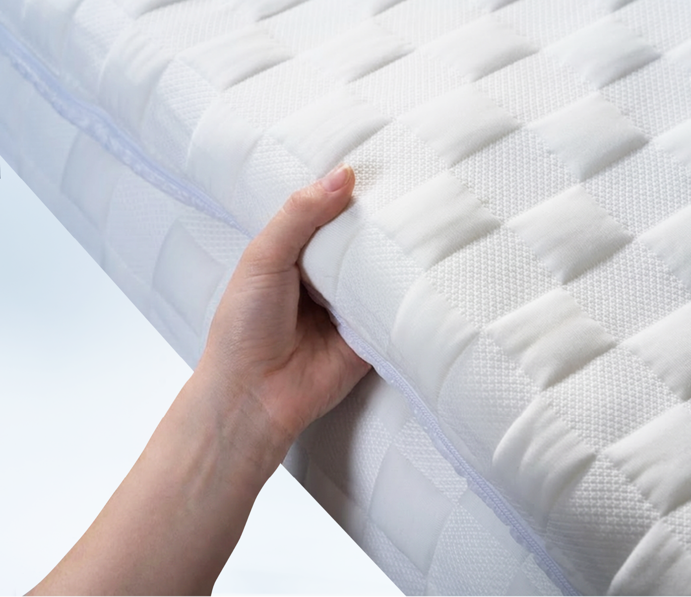 hand grabbing a white posture mattress topper
