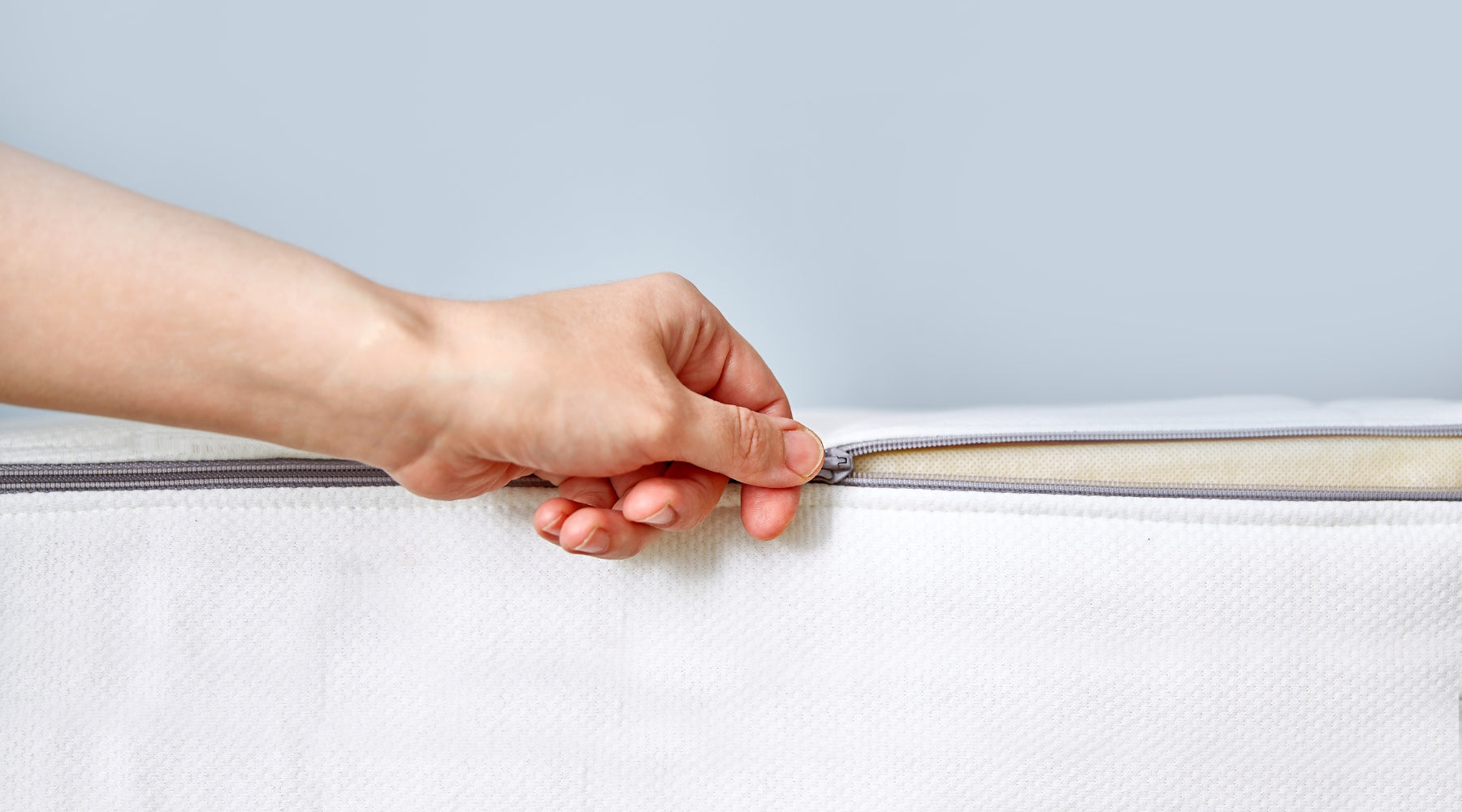 hand opening the zip of a mattress