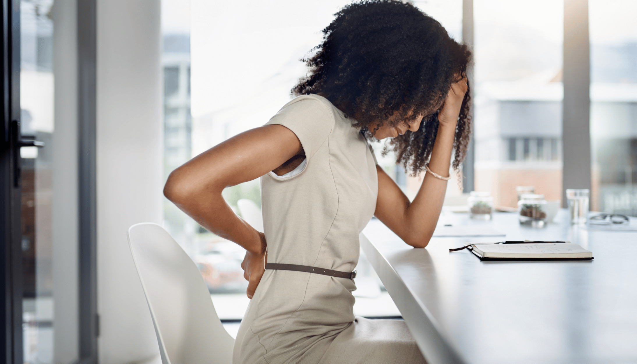 tired woman suffering from back pain at the office