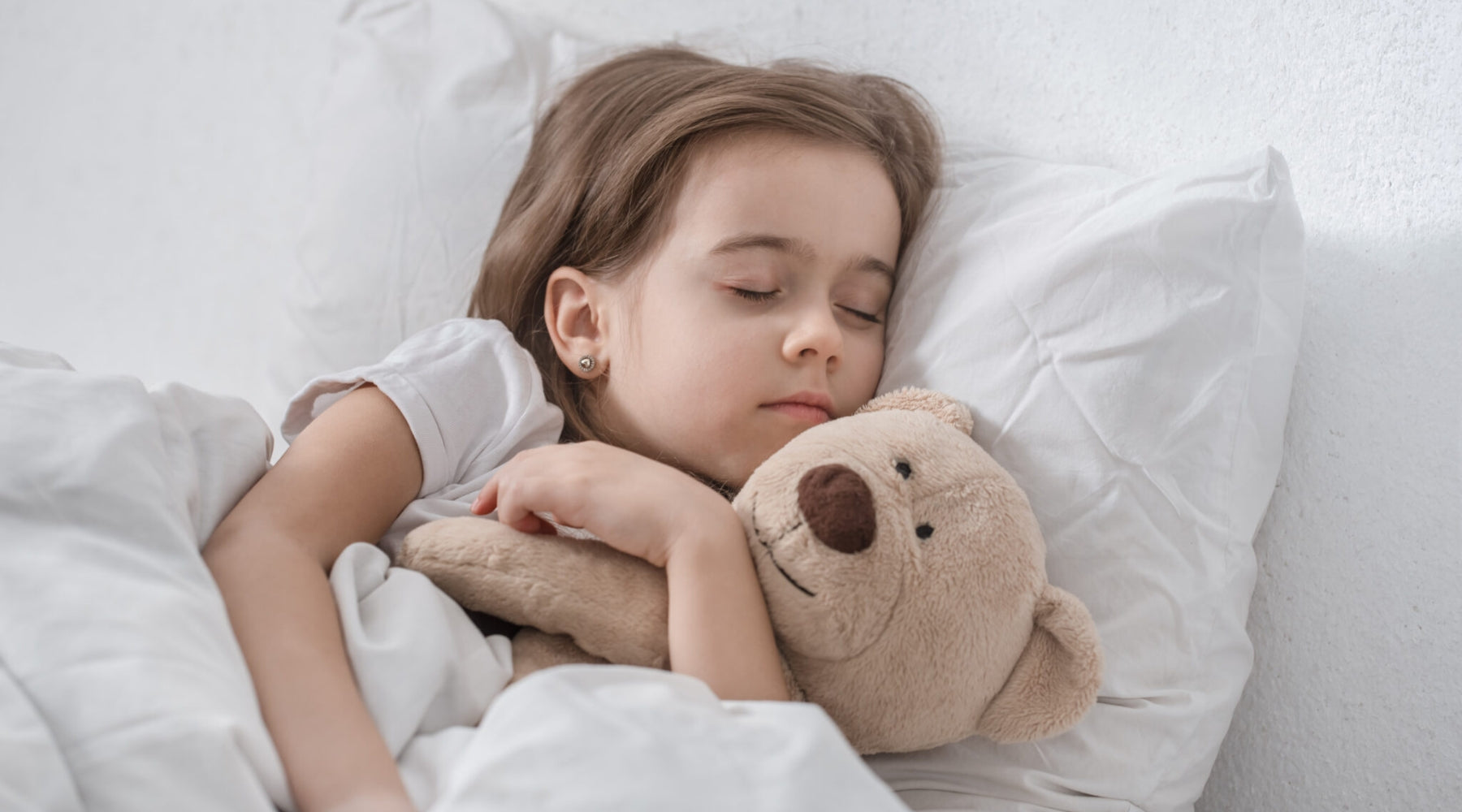 girl sleeping while holding a teddy bear