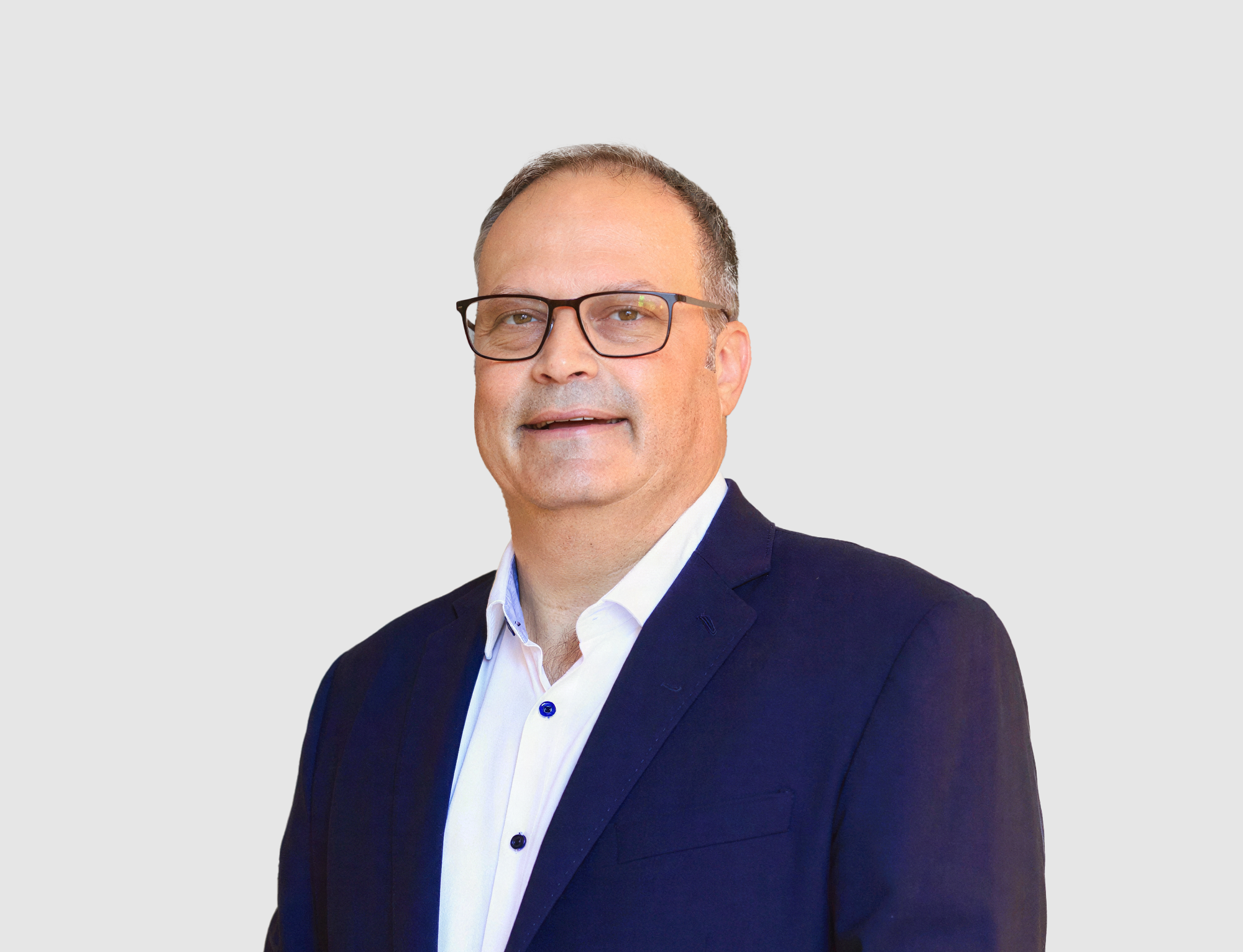 Man wearing glasses and a dark suit on a light gray background