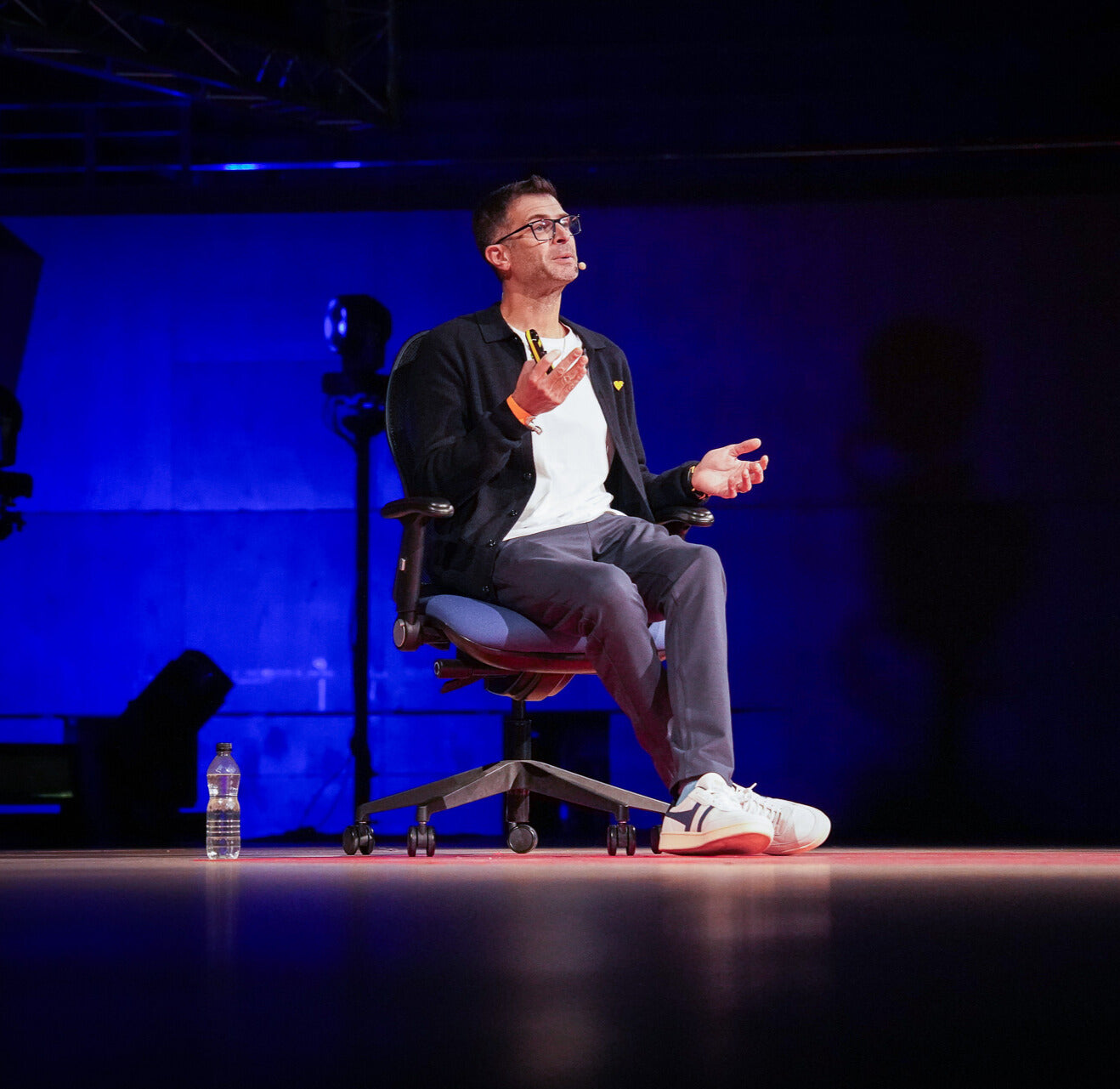 Person sitting on a chair on a stage with a blue background