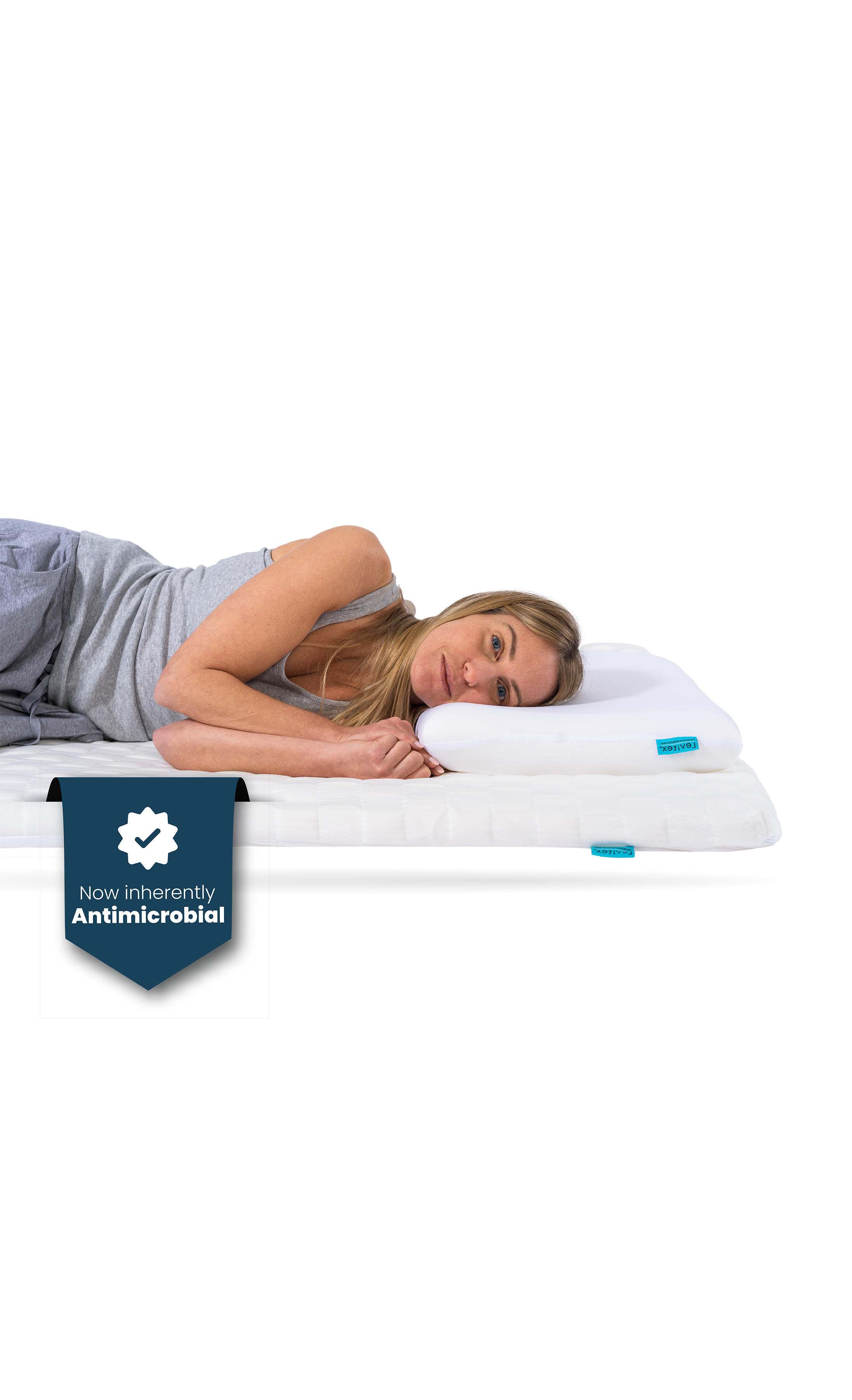 Woman lying on a white posture matttress topper, wearing gray pajamas, on a white background.