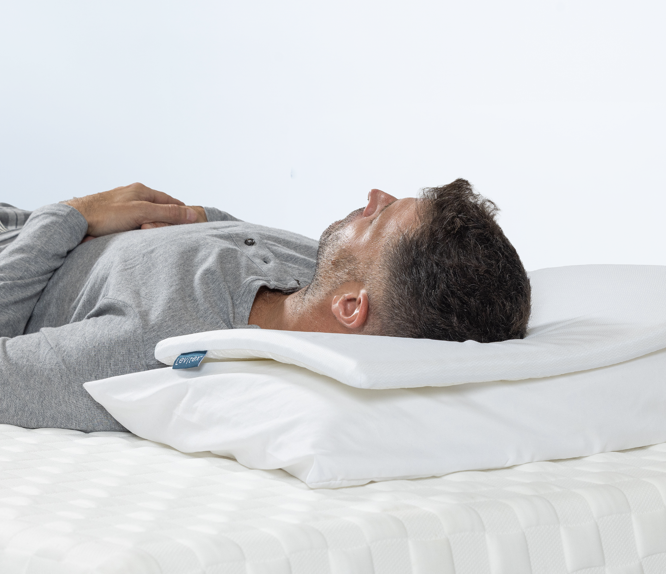 Man lying on his back supported by pillow topper