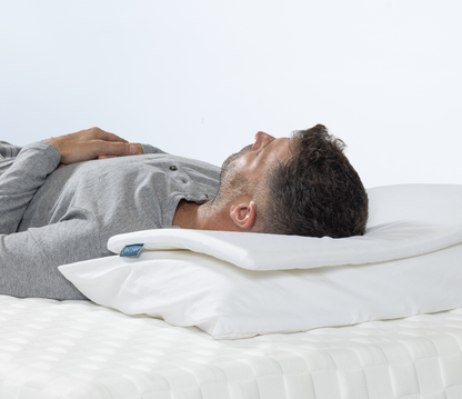 Man lying on his back supported by pillow topper