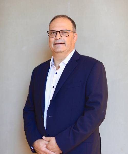 Medical Director of Levitex standing by a grey background in a navy suit