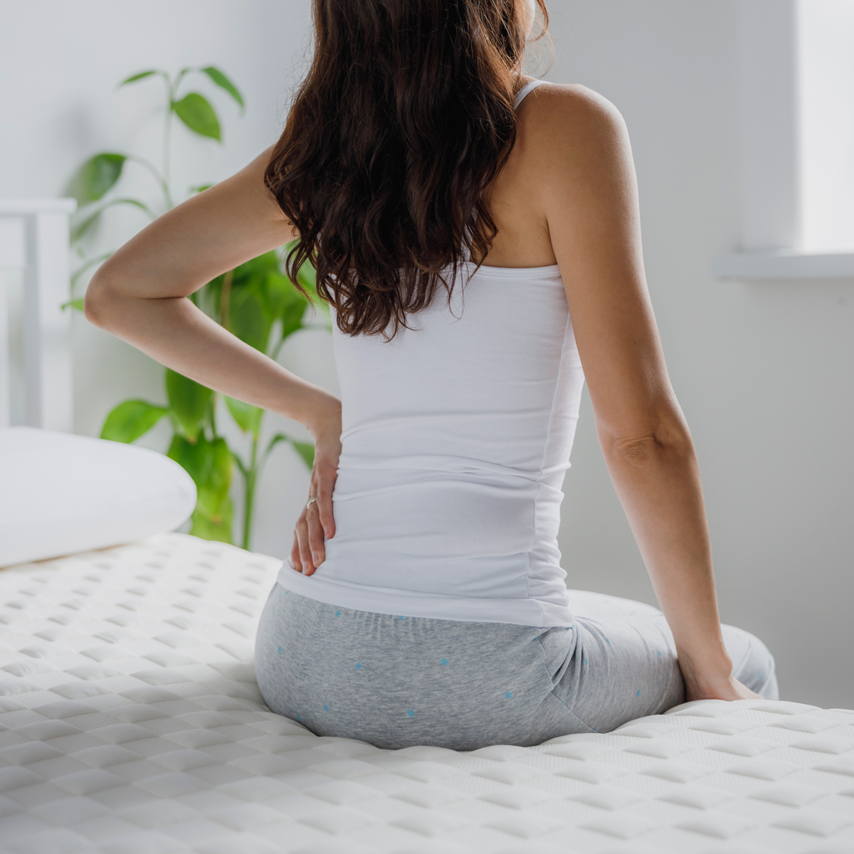 woman with back pain sitting on a bed