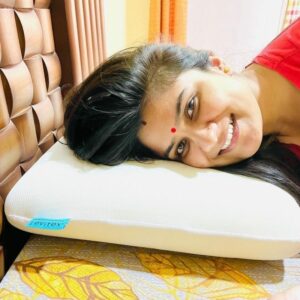 smiling woman with a red dot on her forehead posing on a levitex in her bed
