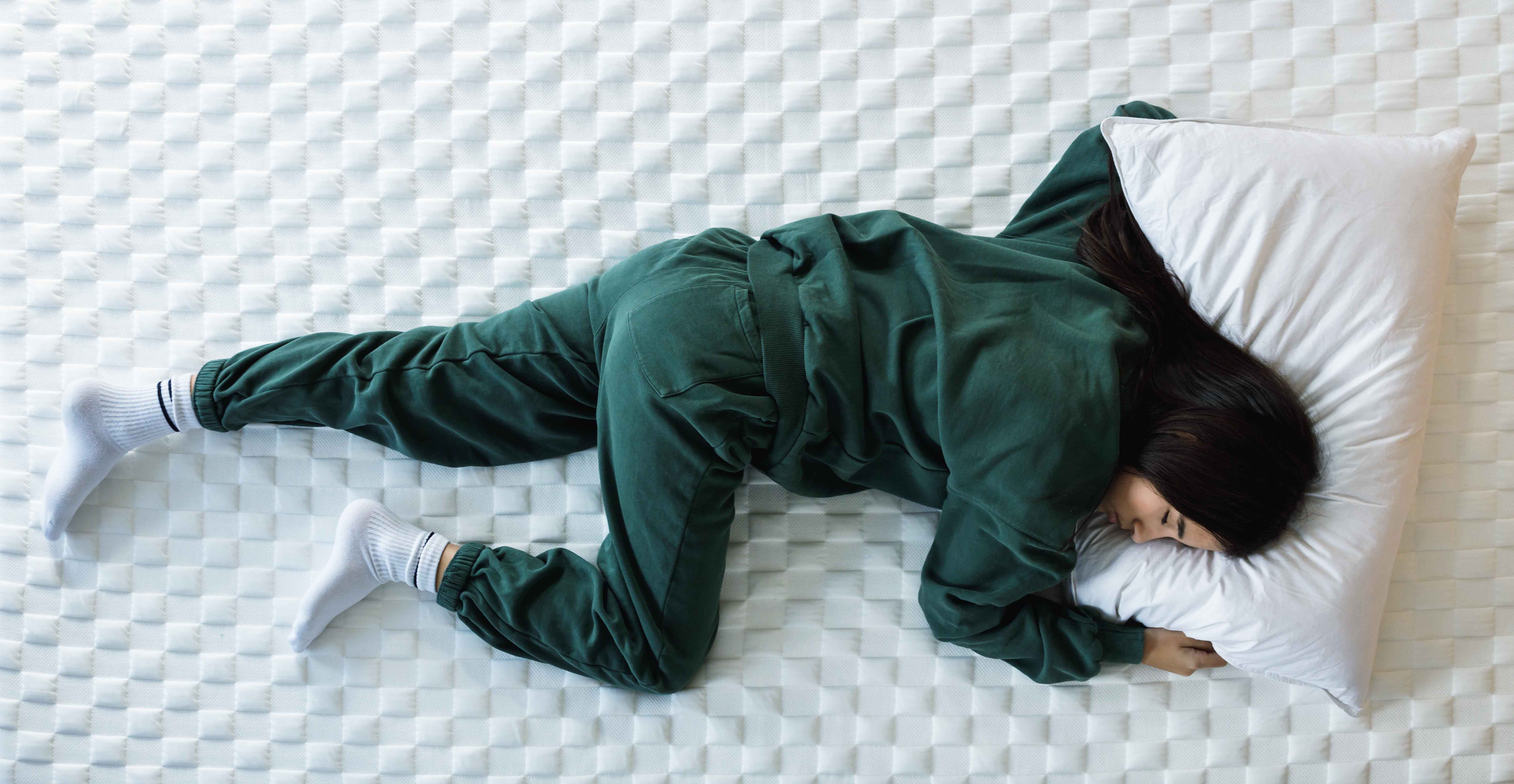 girl in green pyjamas, lying on her front on a bed with her head on a pillow