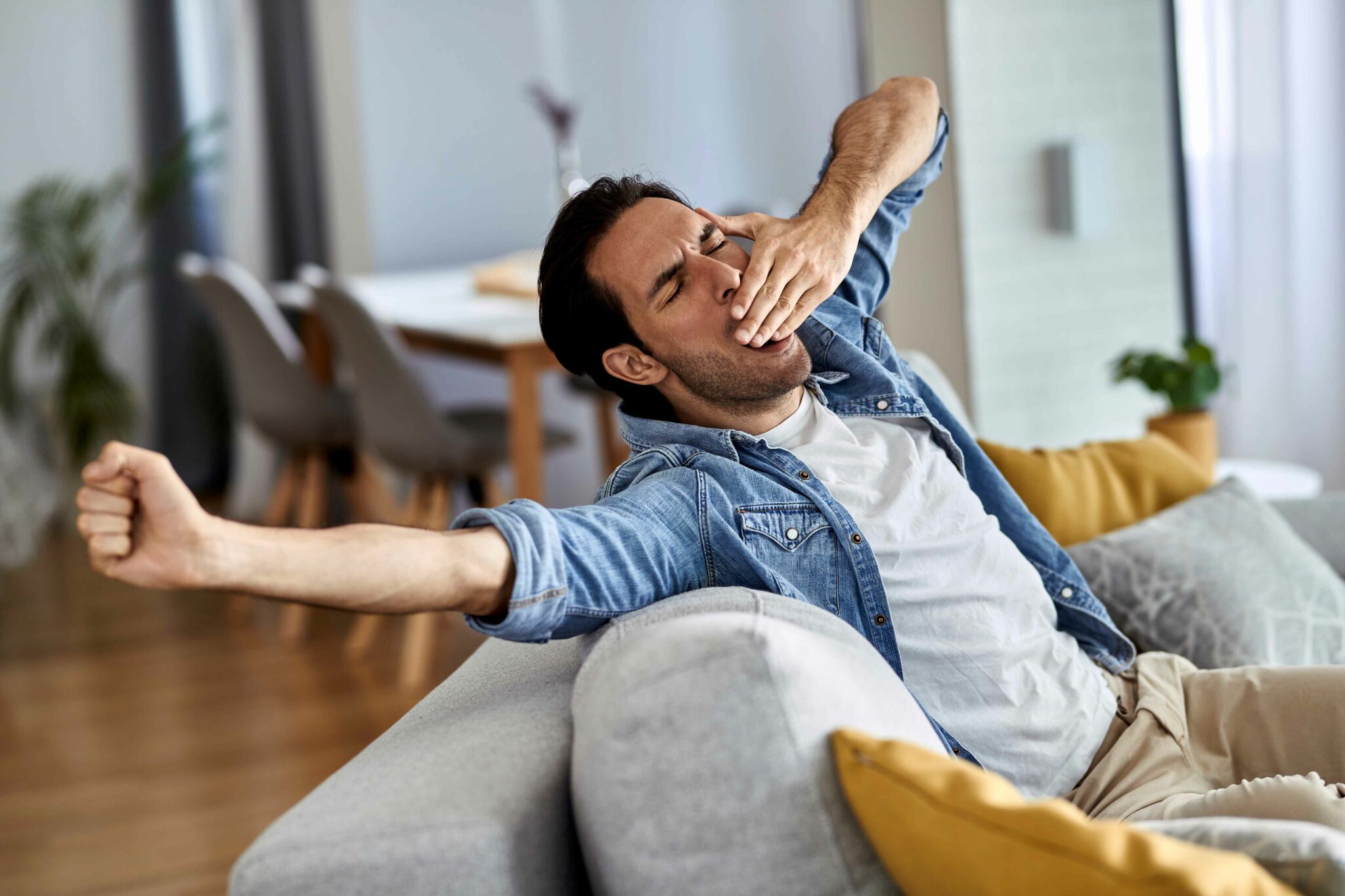 Man stretching and yawing on sofa