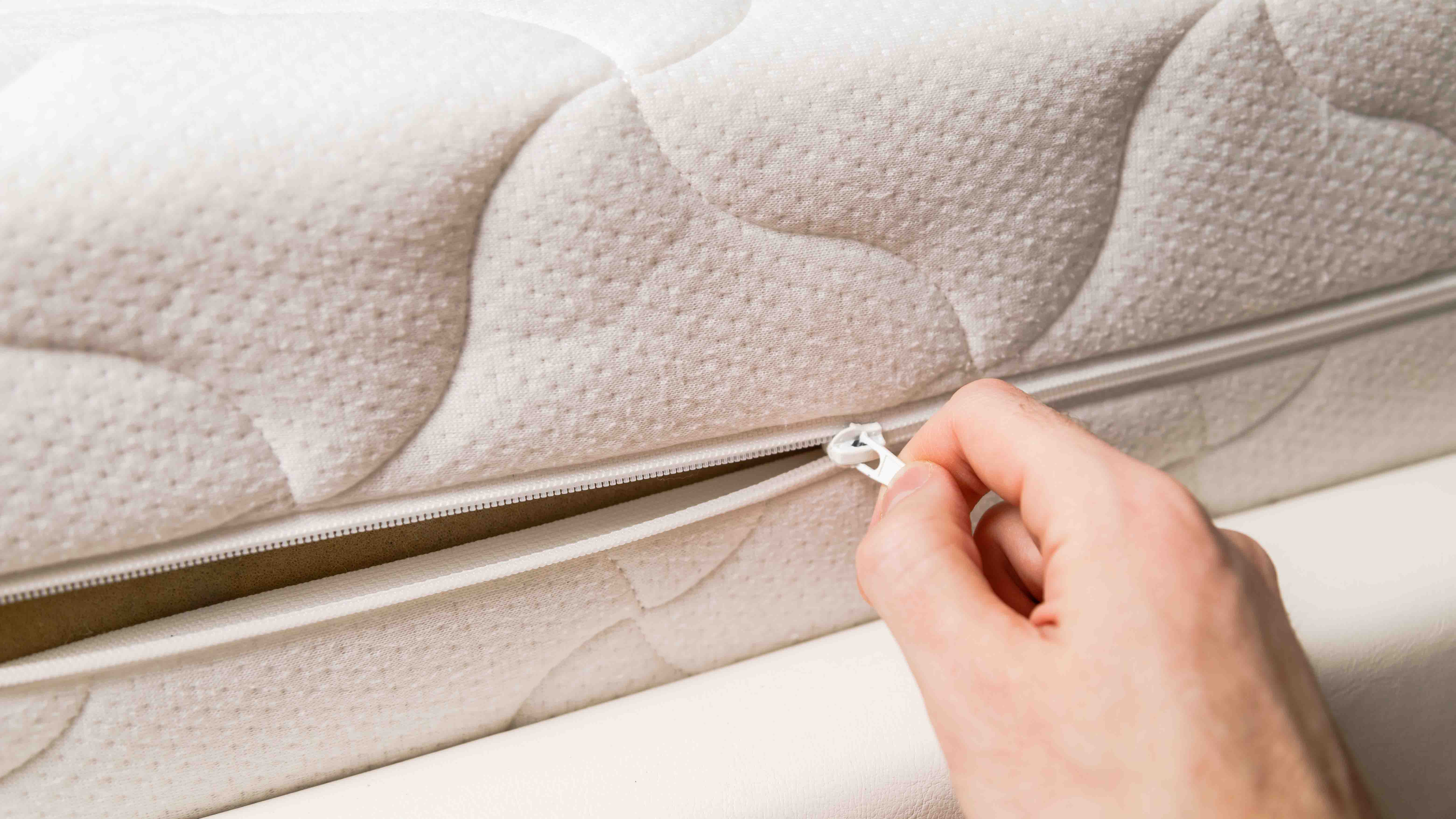Hand opening the zip of a mattress