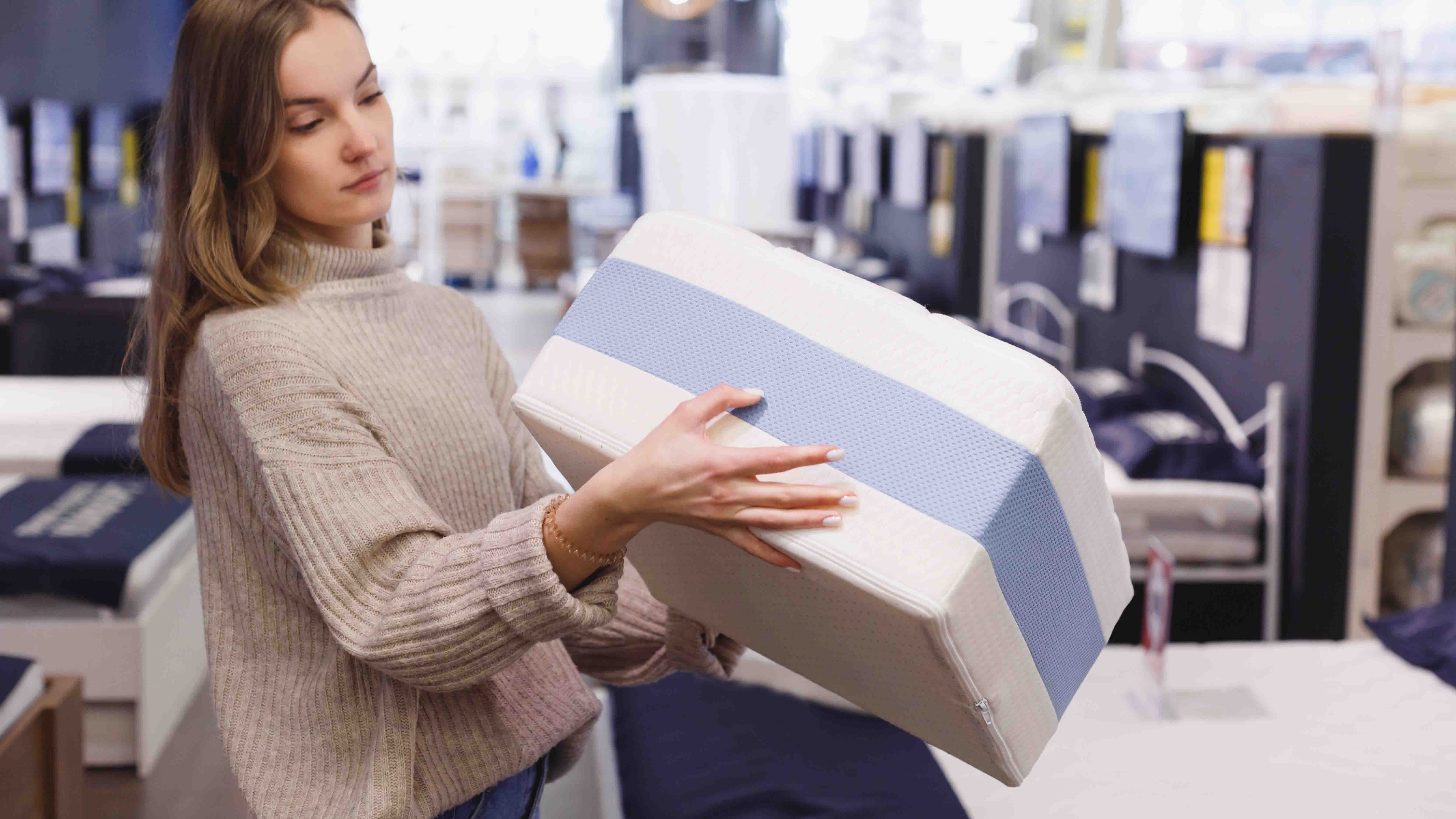 Woman holding mattress sample in showroom