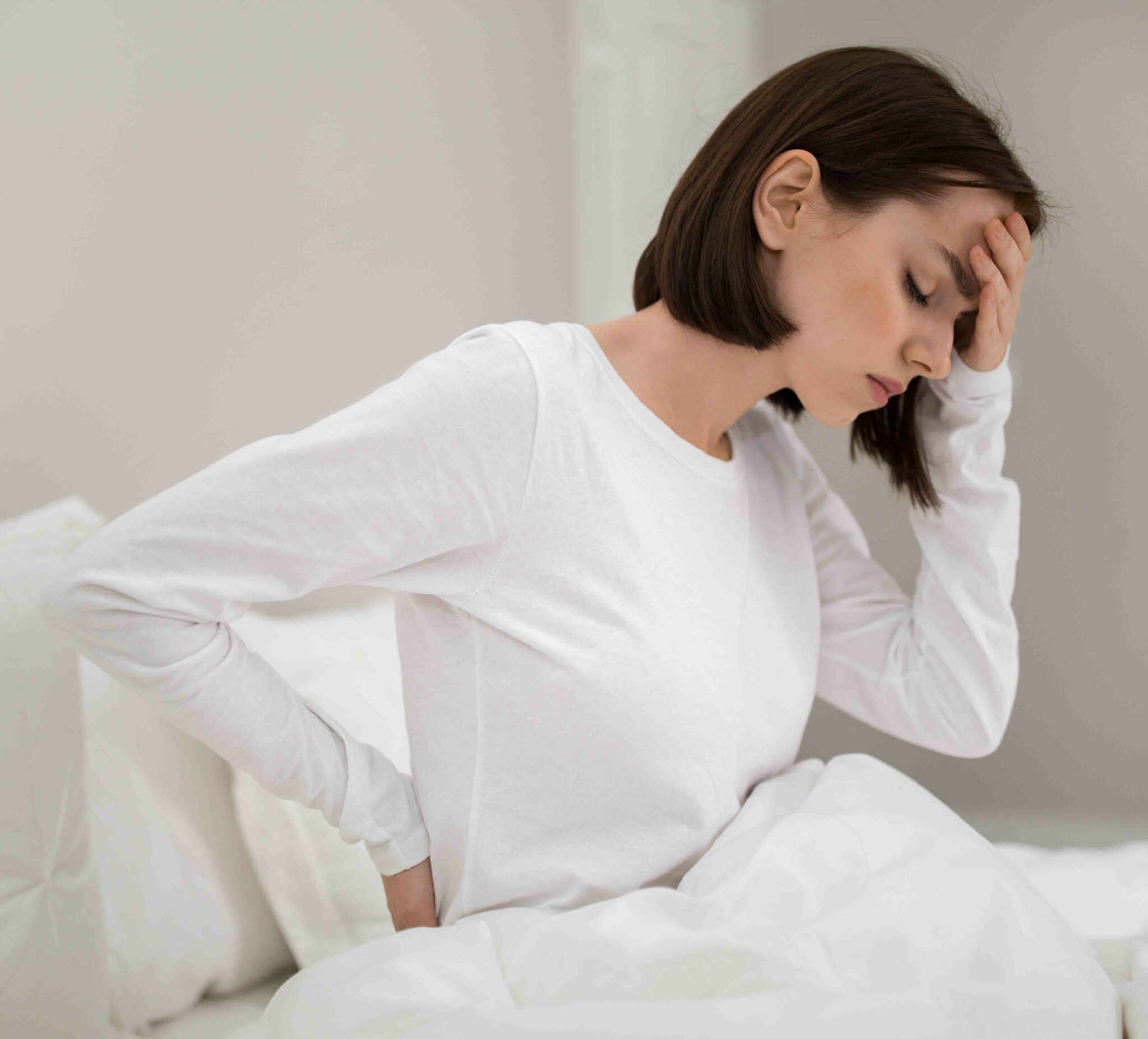 tired woman suffering from back pain in bed